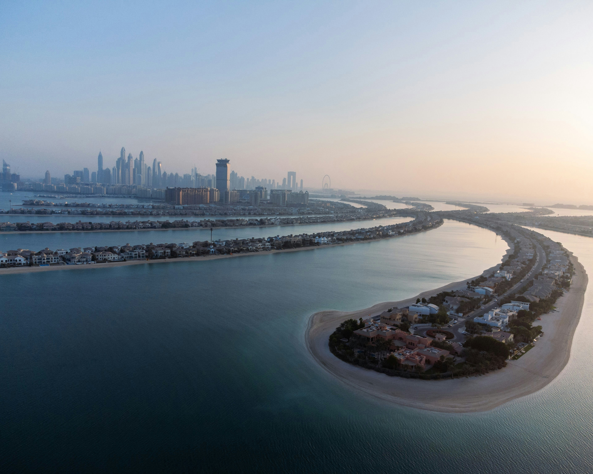 Aerial view of Palm Jumeirah villas with Dubai Marina skyline at dawn