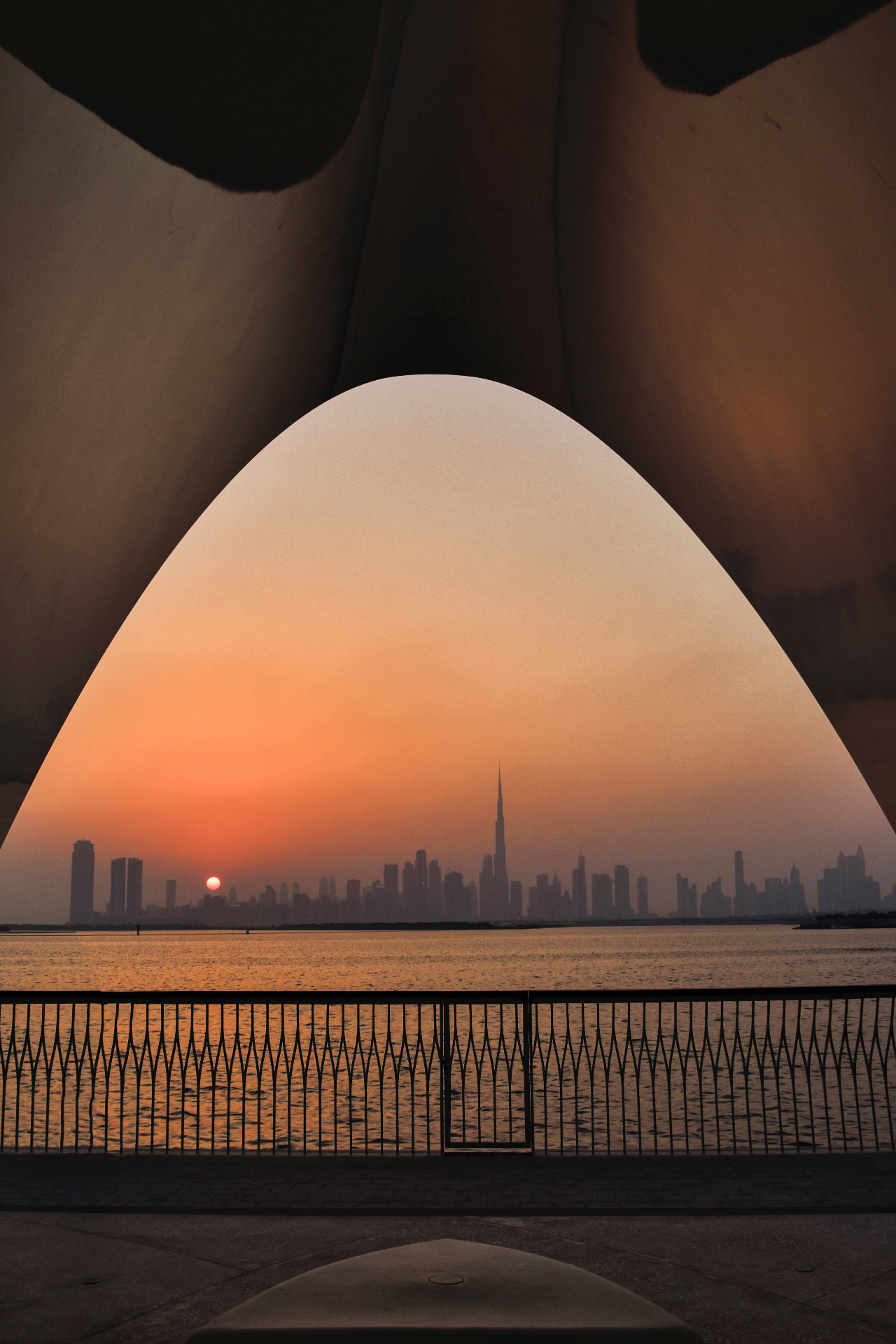 Dubai skyline framed through an architectural arch at sunset with Burj Khalifa